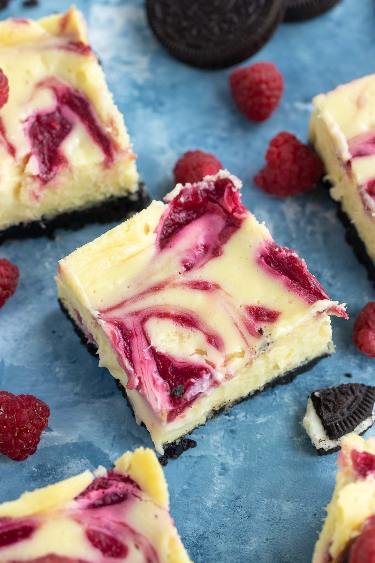 white chocolate raspberry cheesecake bars on blue background