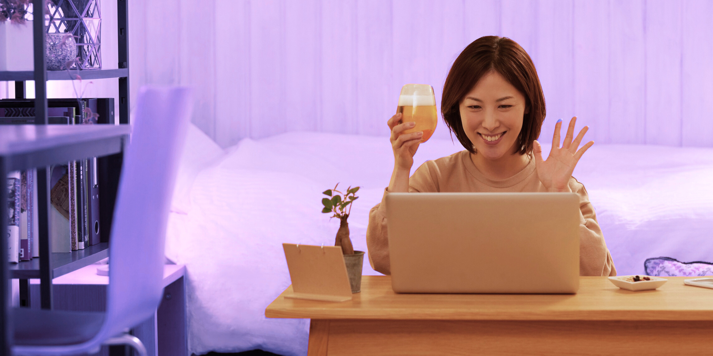 Remote team member smiling and raising a glass during a virtual happy hour video call, showing virtual team building activities that foster collaboration and enhance remote team communication.