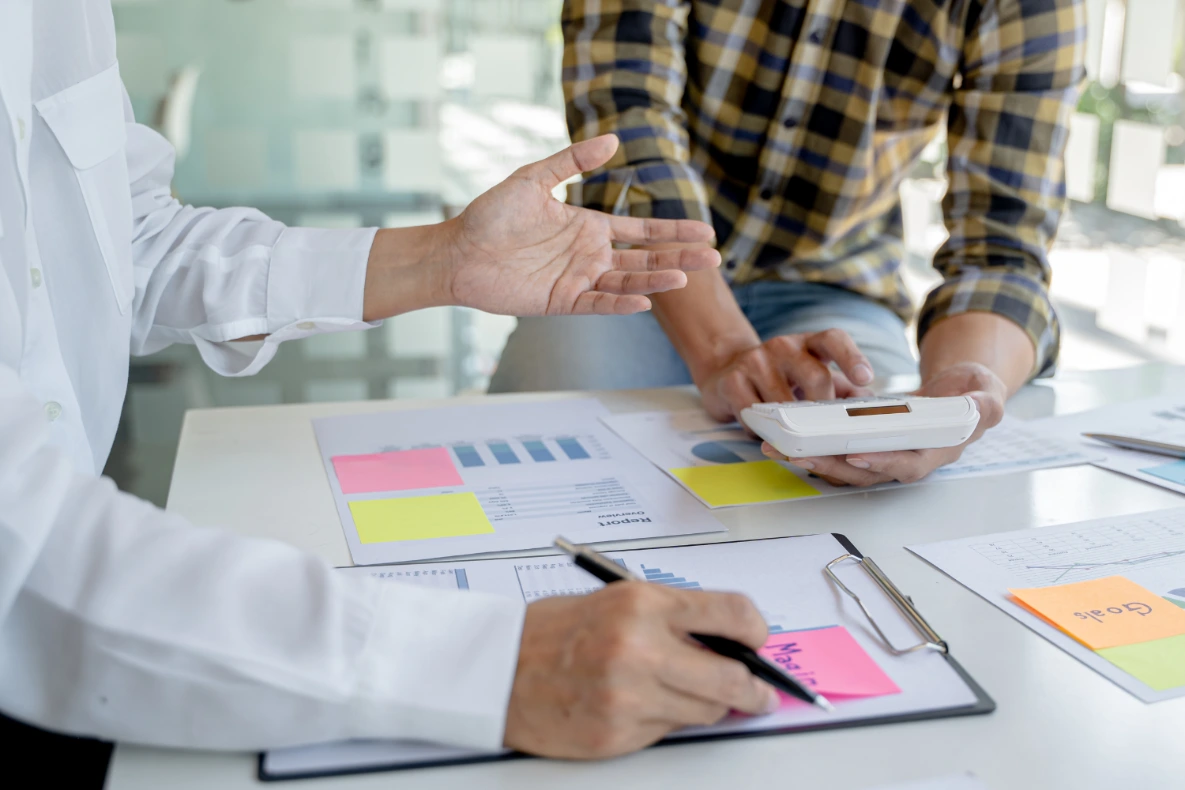 Two people review charts and graphs on a table.