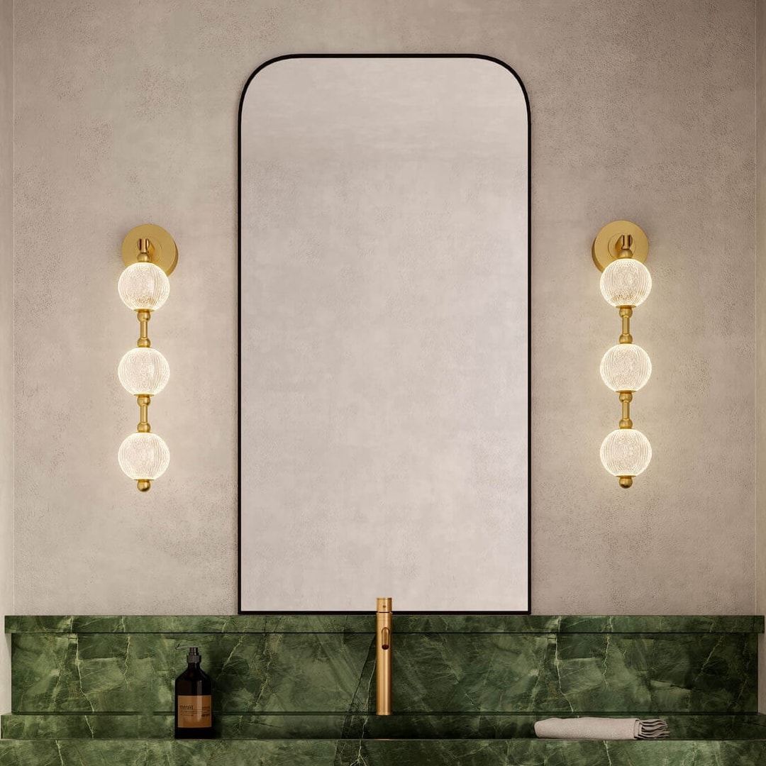 Elegant bathroom wall lights with gold accents and globe bulbs flanking a tall mirror, offering a stylish mix of modern and classic lighting ideas.