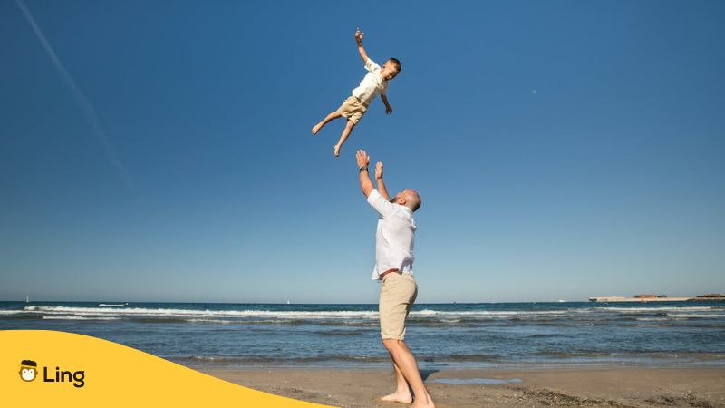 Father throwing son up on beach