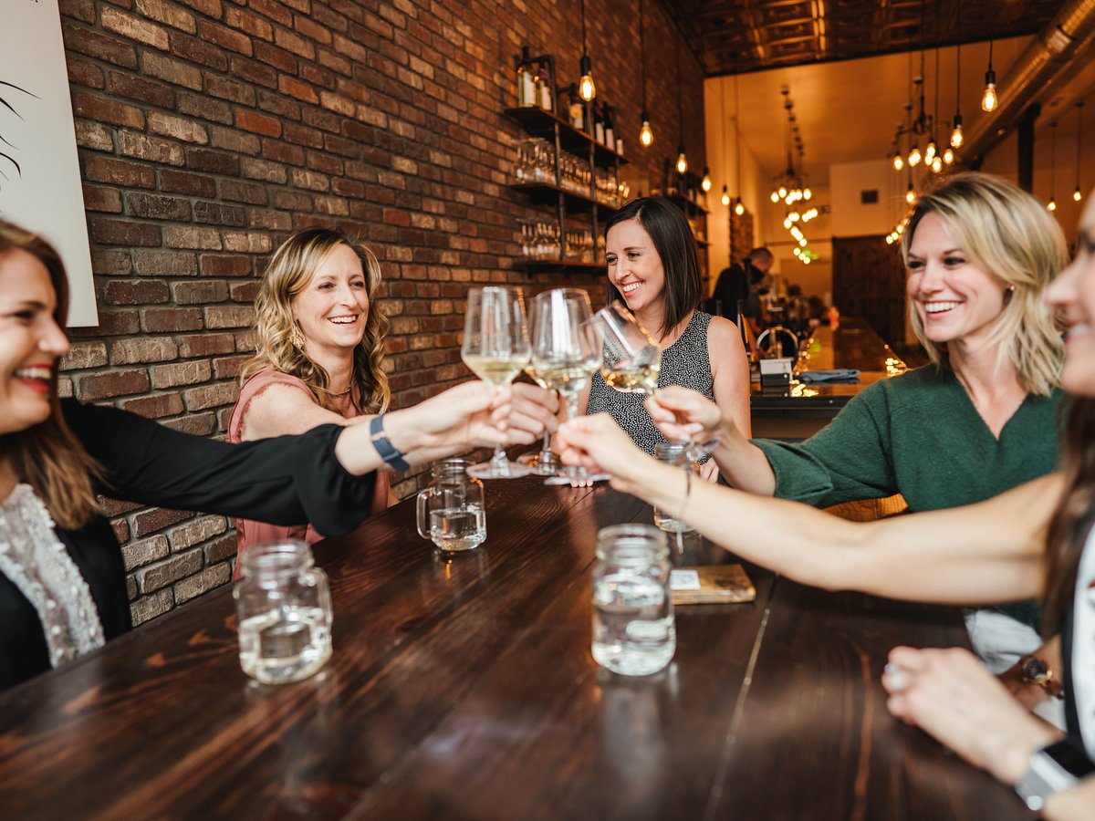 Young people celebrating together drinking red wine glasses on patio garden  at summer party. Diverse friends having fun cheering glasses during dinner  party. Friendship and celebration concept Stock Photo