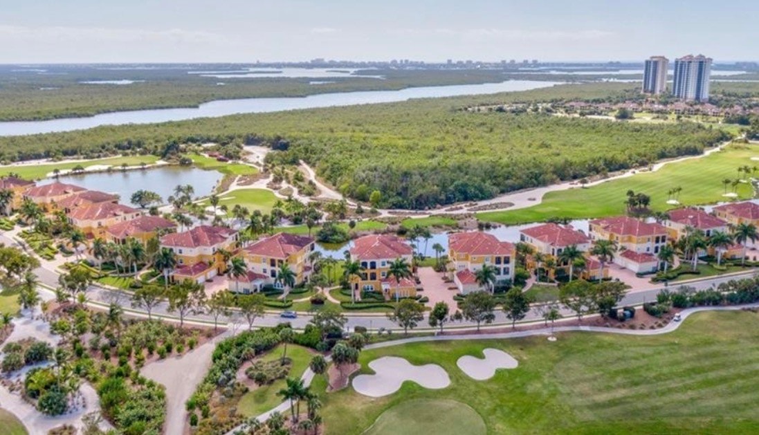 The image features a luxurious tower residence interior with stunning floor-to-ceiling windows that provide breathtaking views of the golf course and nearby water, showcasing the elegance of Hammock Bay Golf and Country living. The spacious layout includes an expansive living area and a sophisticated design, perfect for enjoying the resort-style lifestyle in this exclusive community.