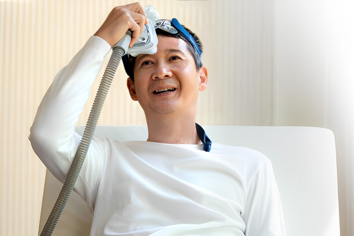 A photo of a man smiling while holding his CPAP Mask