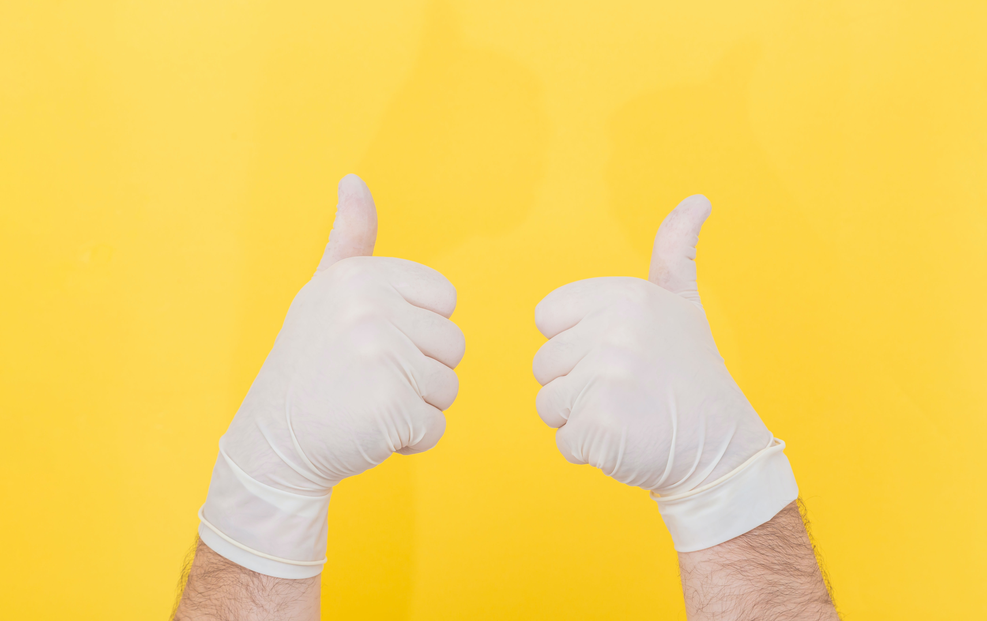 Two thumbs up wearing rubber gloves. Open auto transport carriers. Affordable car transportation.