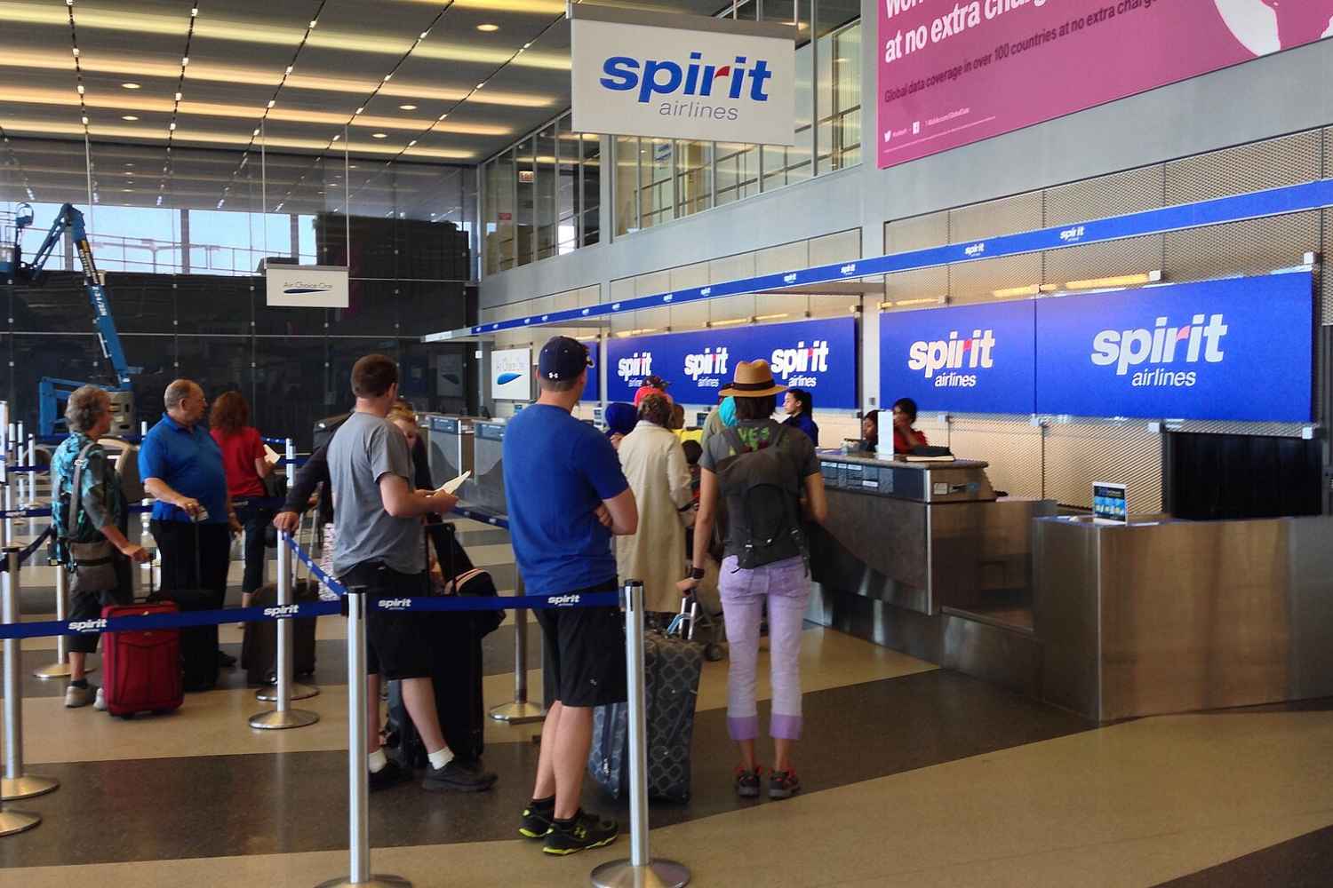 passengers waiting in queue for cheking in their luggage at the spirit airlines check in counter: why are spirit and frontier so cheap
