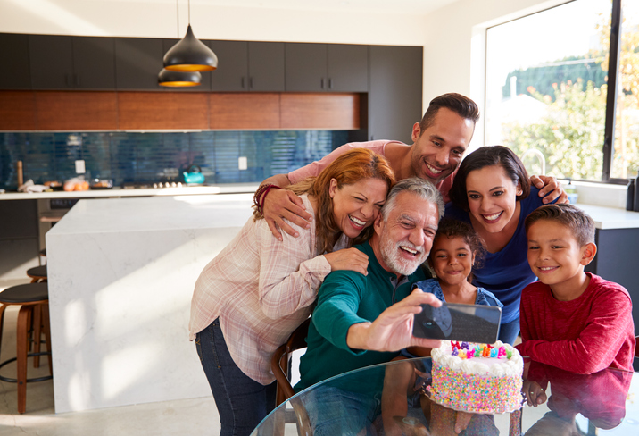 Happy family smiling and taking a selfie around a birthday cake.