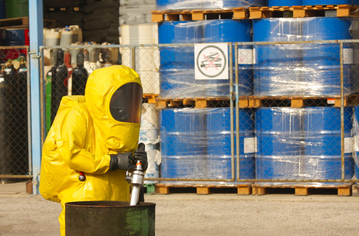 Warehouse worker in shell suit standing near hazardous chemicals