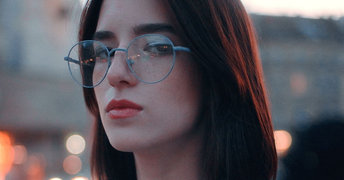 Focused woman with straight red hair and glasses, emphasizing focus on tax benefit rule strategies.