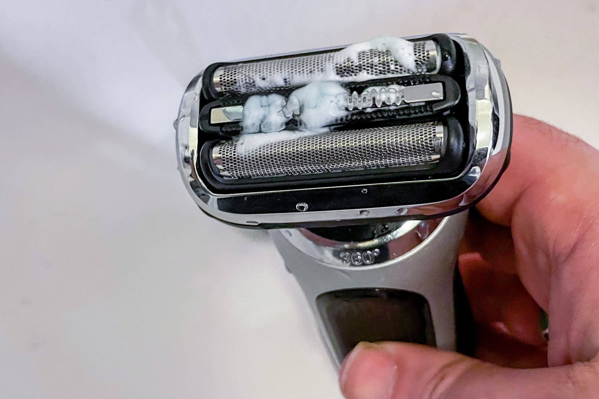 A person doing electric shaver care for electric razors with shaving cream and rotary shaver and spray cleaner