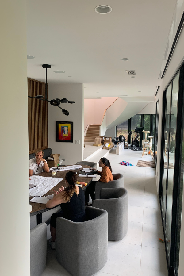 designers and contractors meet on a job site around a wooden table in gray club barrel chairs