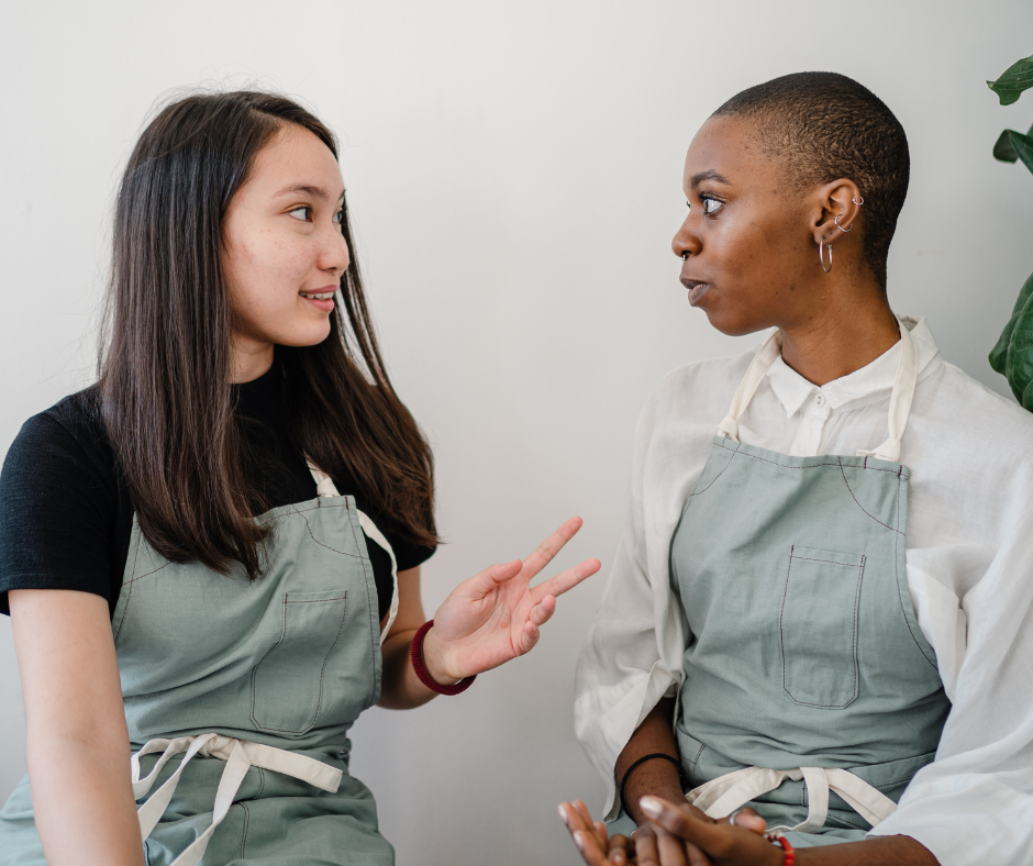 two women wearing aprons discuss their work