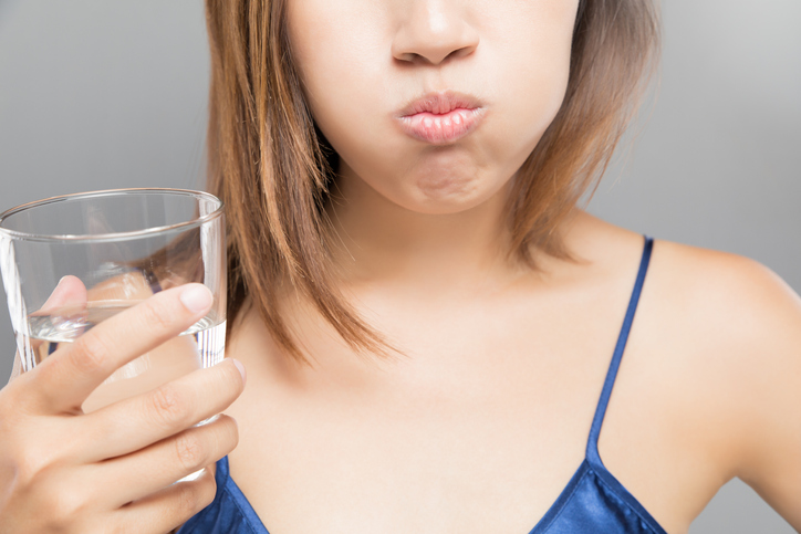 An image of a woman with a mouthful of water preparing to gargle. 