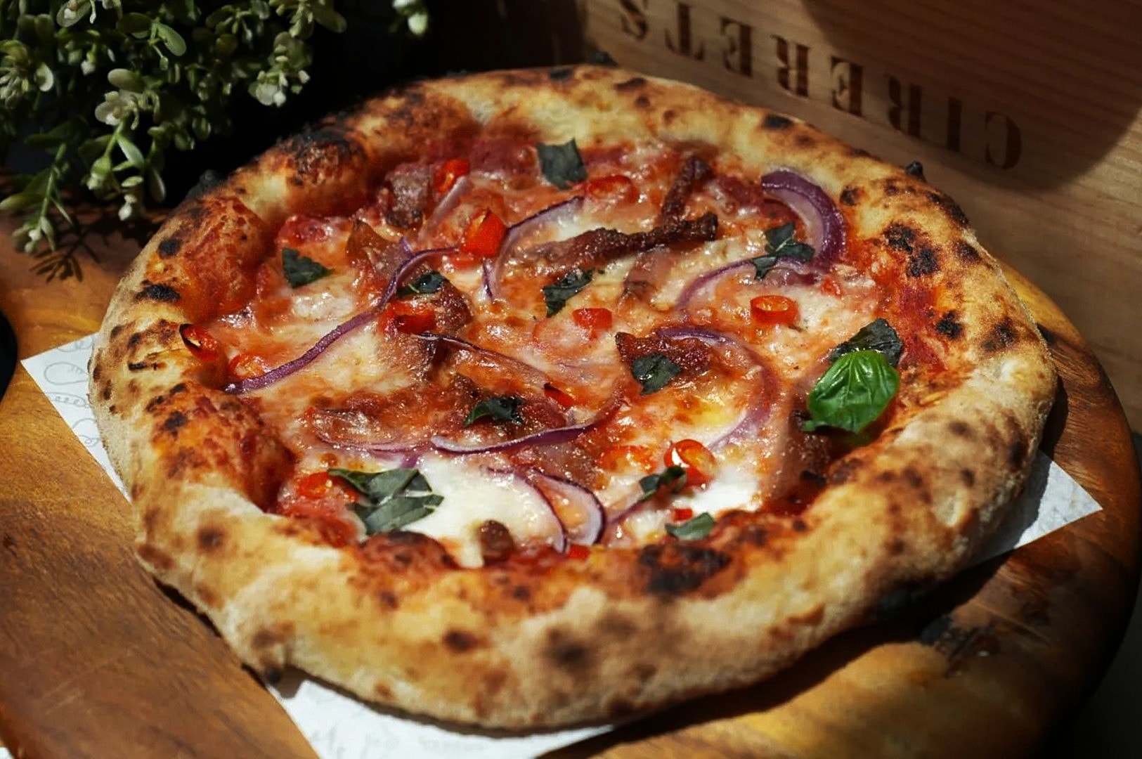 A delicious American-Italian pizza featuring red onions and cheese, displayed on a rustic wooden table in Singapore.