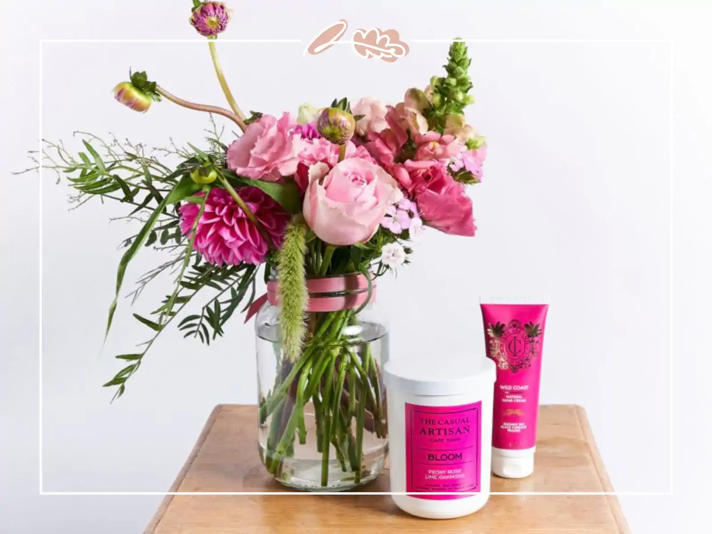 Floral arrangement in a glass vase with pink roses and greenery, accompanied by skincare products, Fabulous Flowers and Gifts