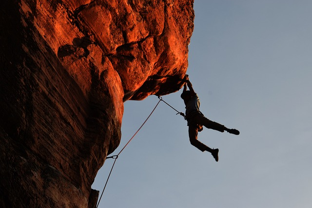 Image by wallace769 from Pixabay. Man rock climbing on red rock, swinging in air. 