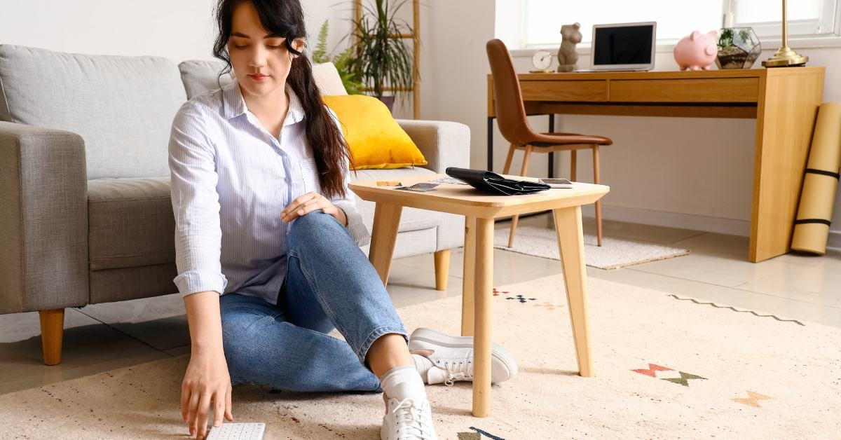 Woman sitting on the floor working on tax planning strategies with financial documents and calculator.