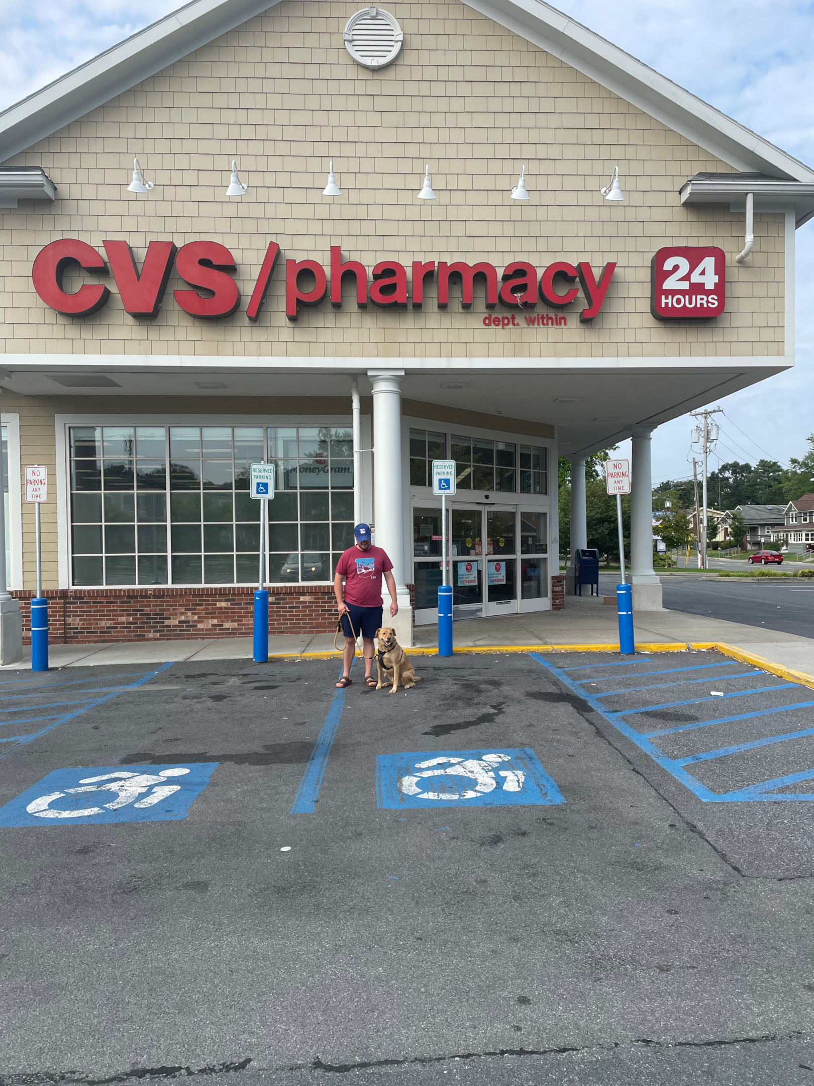 Man standing in front of a CVS store with a leashed dog. 