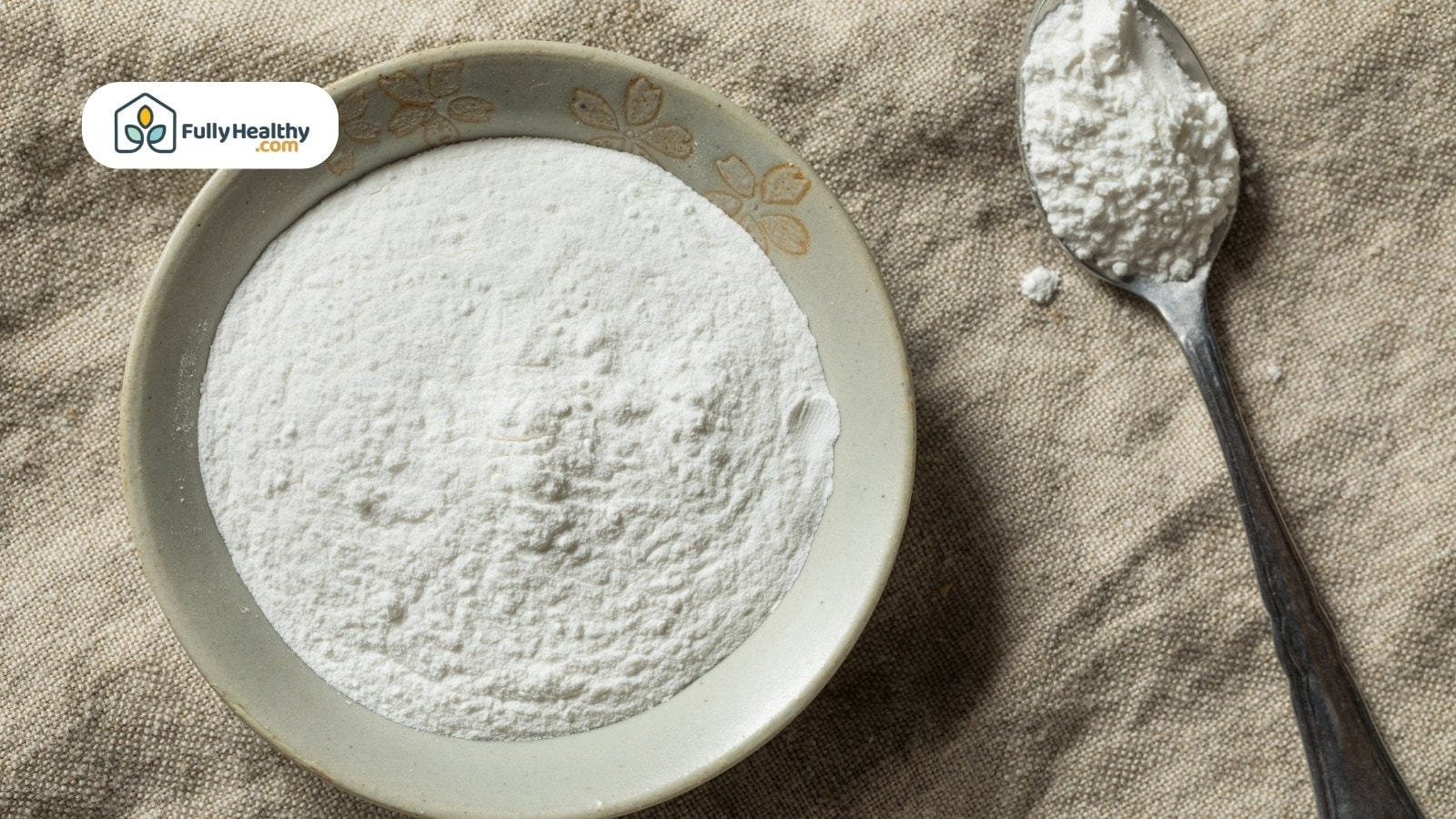 White ceramic bowl filled with cornstarch powder beside metal spoon