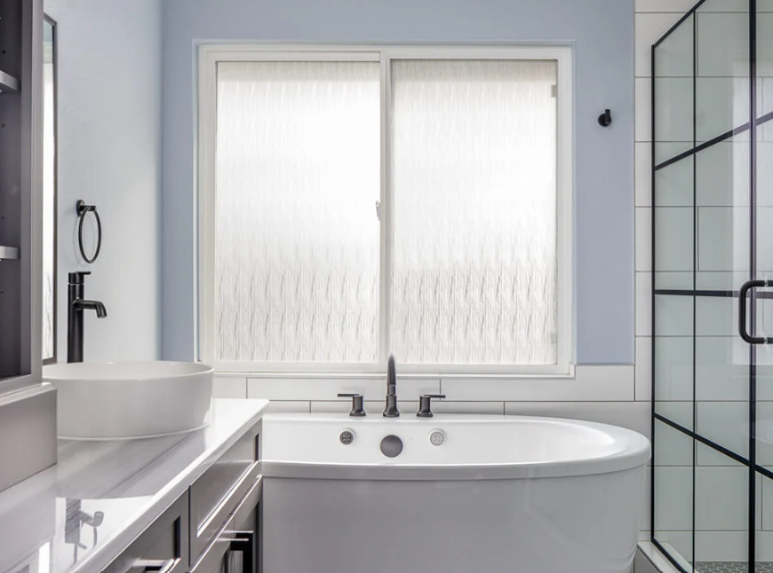 A freestanding tub outside a tiled shower