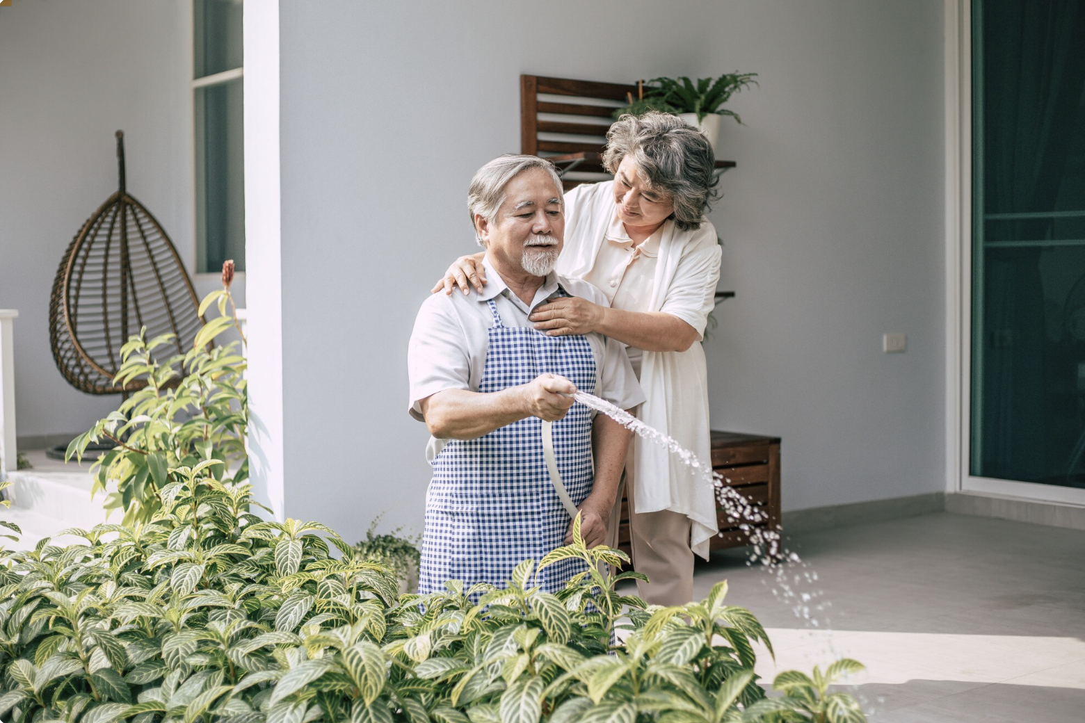 Elderly couple watering plants