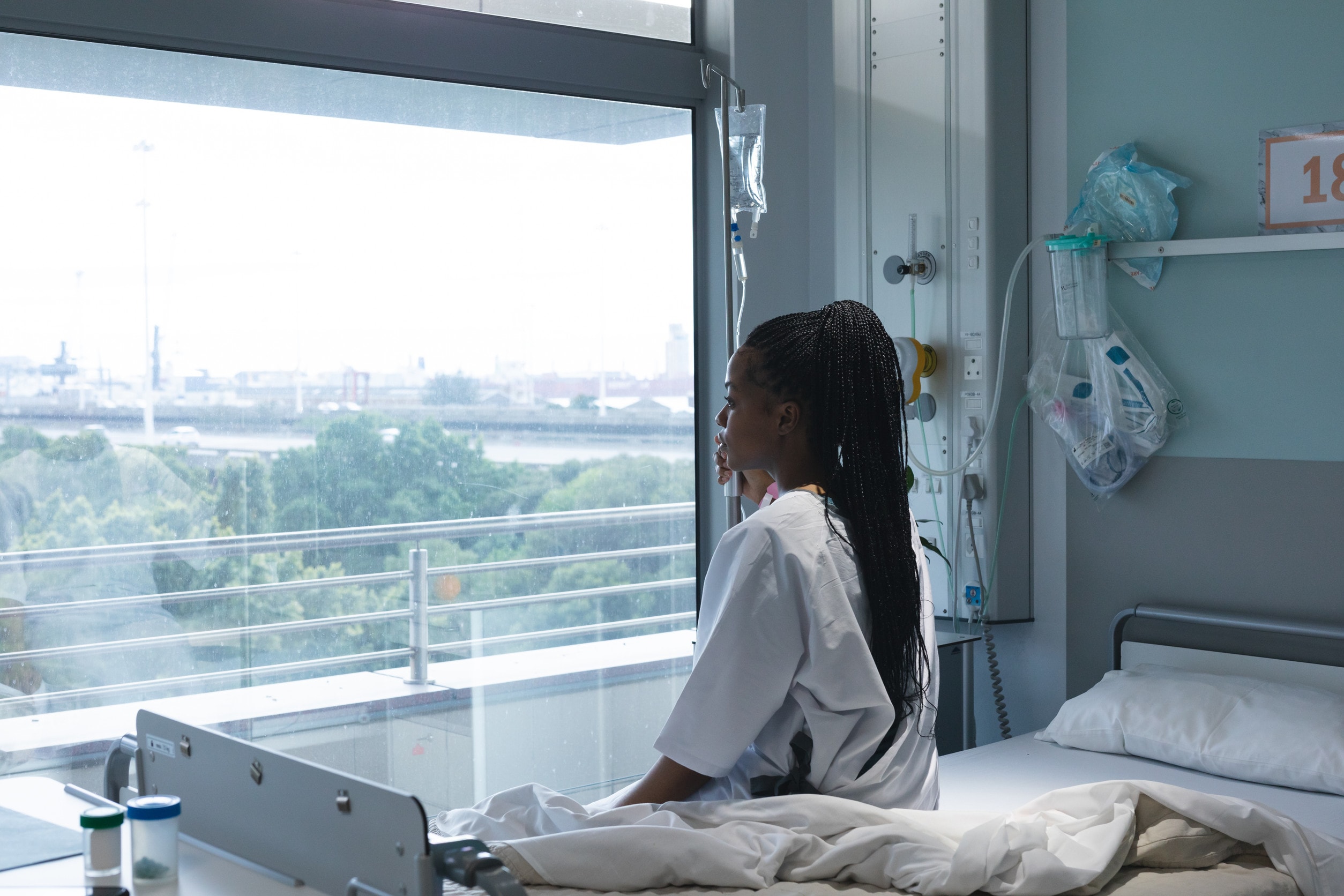 A victim of surgical errors sits on a hospital bed and looks out a window