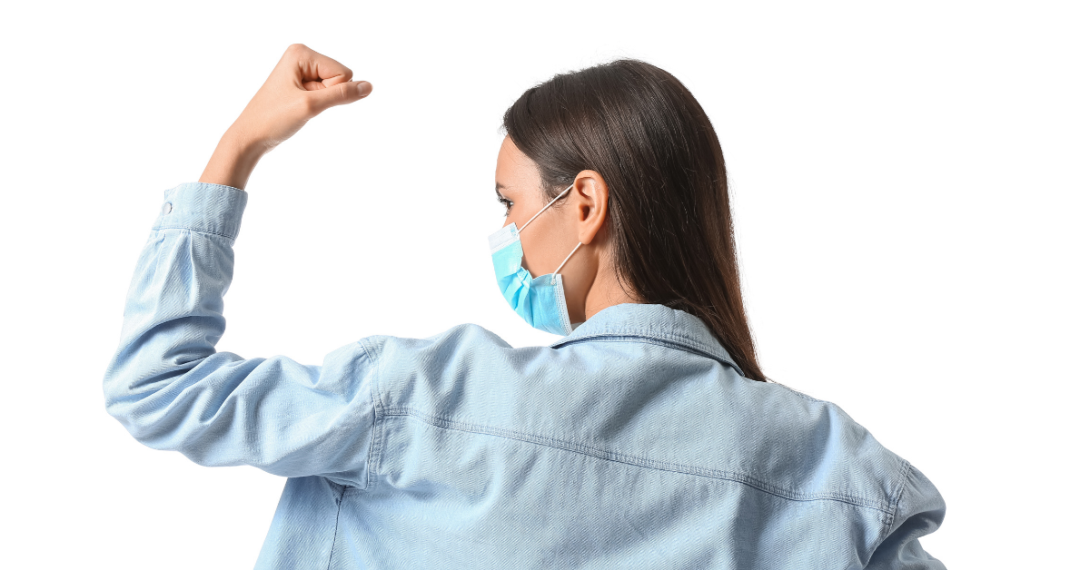 A woman flexing her bicep with a mask on, related to stronger immunity from taking ice baths.