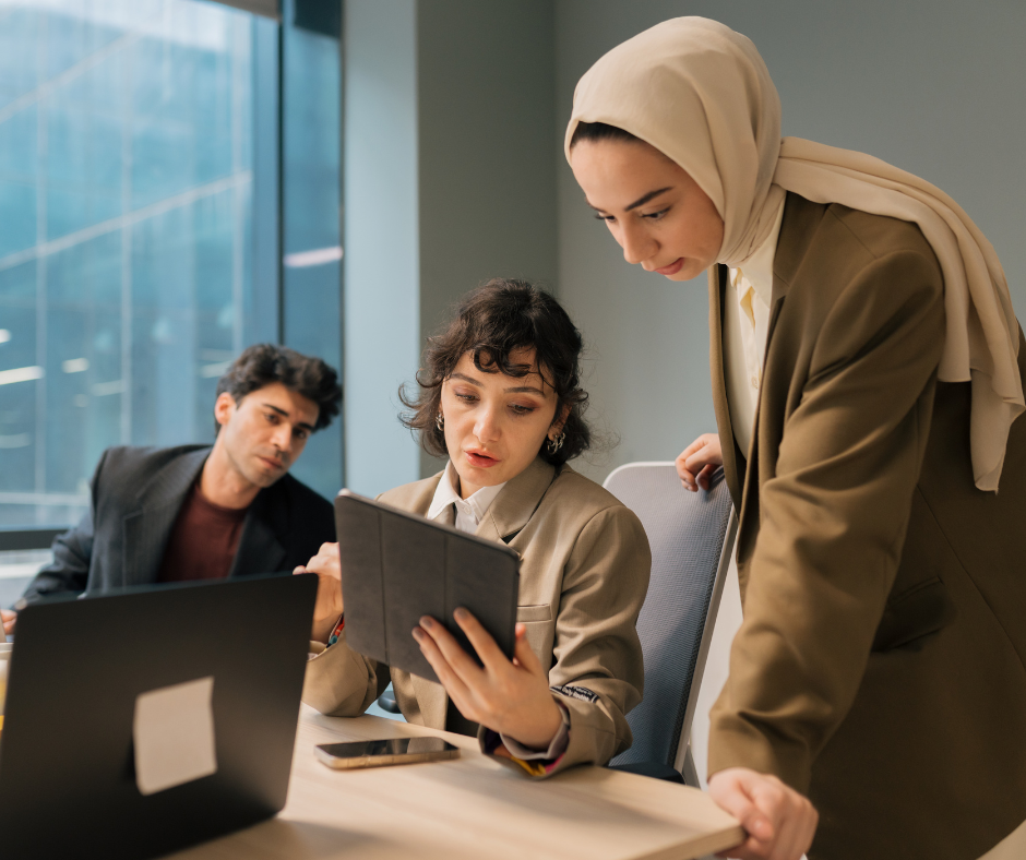 three people gathered around a desk looking at a tablet