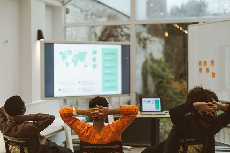 Kollegen, die eine Internetverbindung im Büro nutzen, um eine Powerpoint-Präsentation für einen Ted Talk zu überprüfen und zu bewerten 