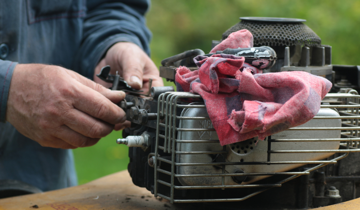 A figure removing the spark plug from a mower engine