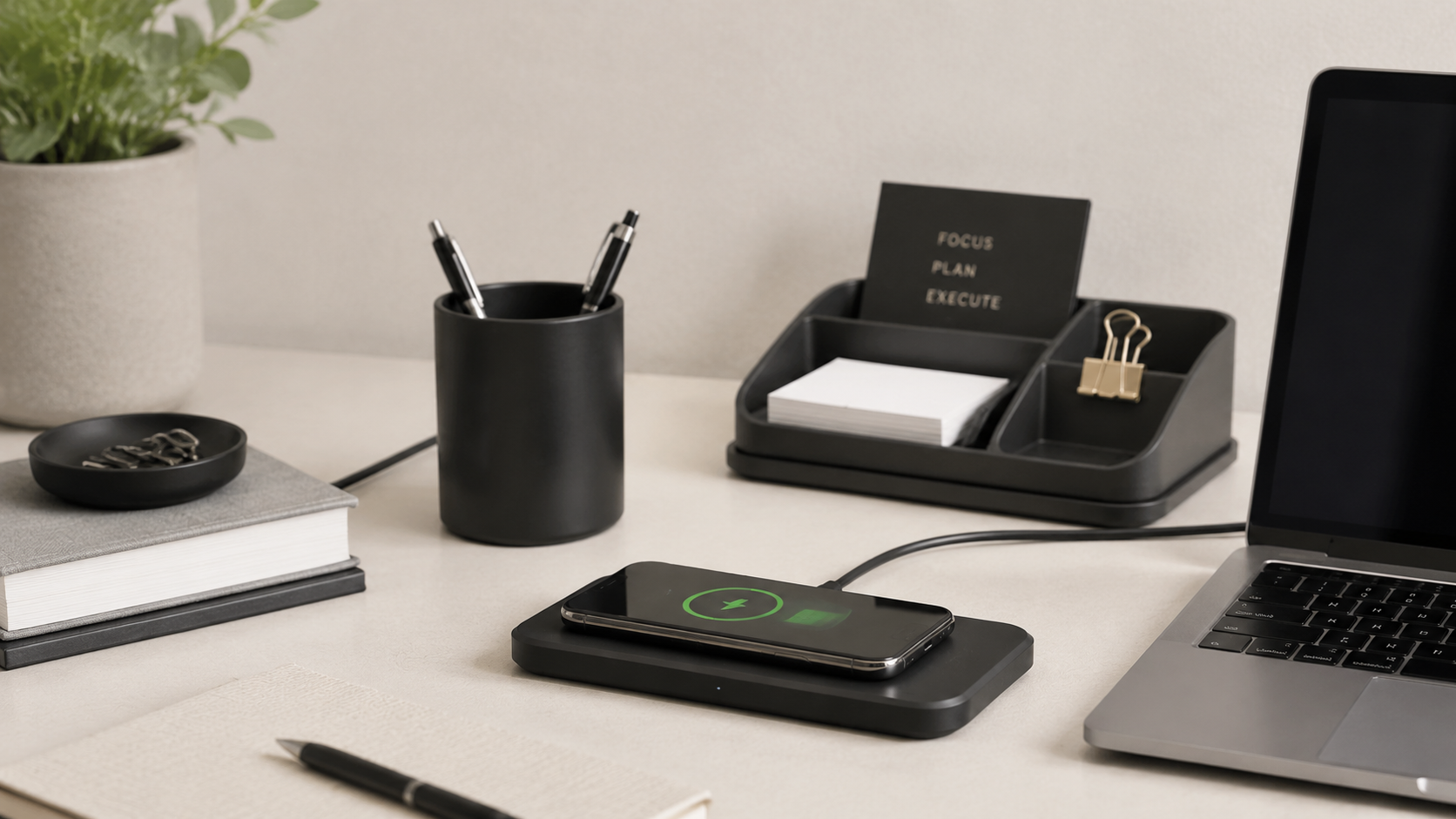 Wireless charging pad and desk organizer beside a laptop and meeting notebook