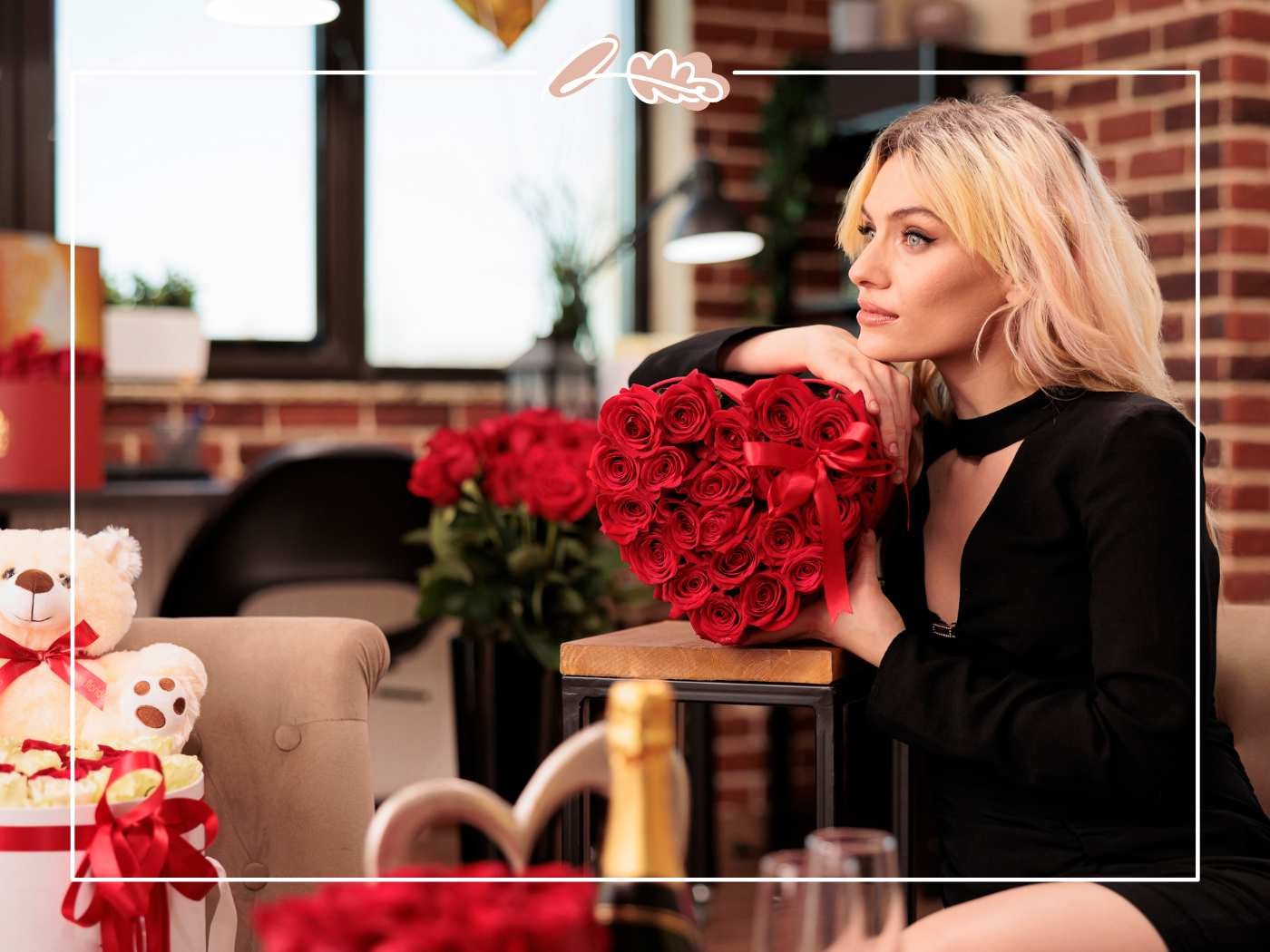 Blonde woman in black holds a heart-shaped red rose box with ribbon in a cosy brick interior, Fabulous Flowers border.