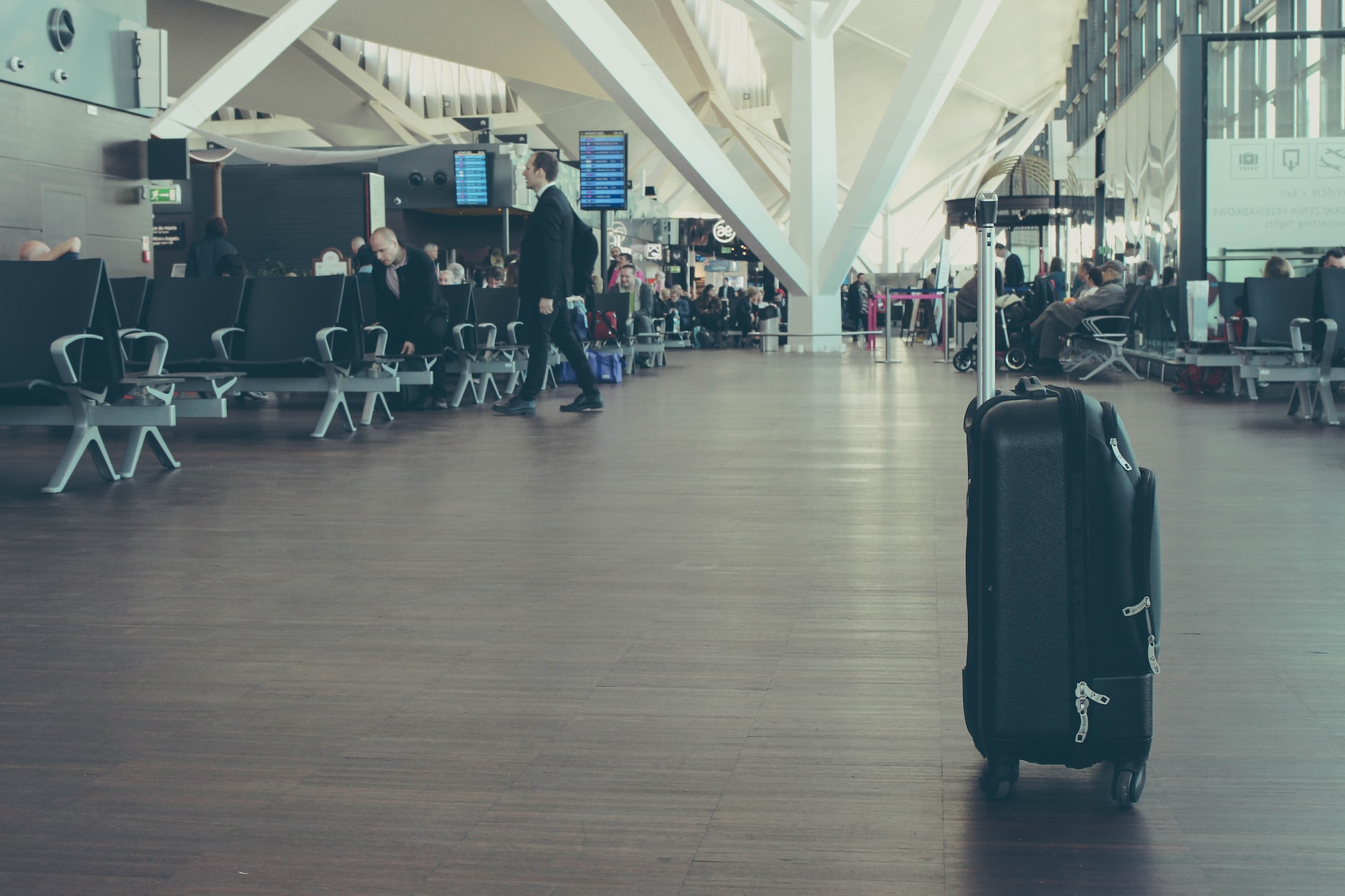 Lost items at an airport terminal: a black suitcase standing without its owner.