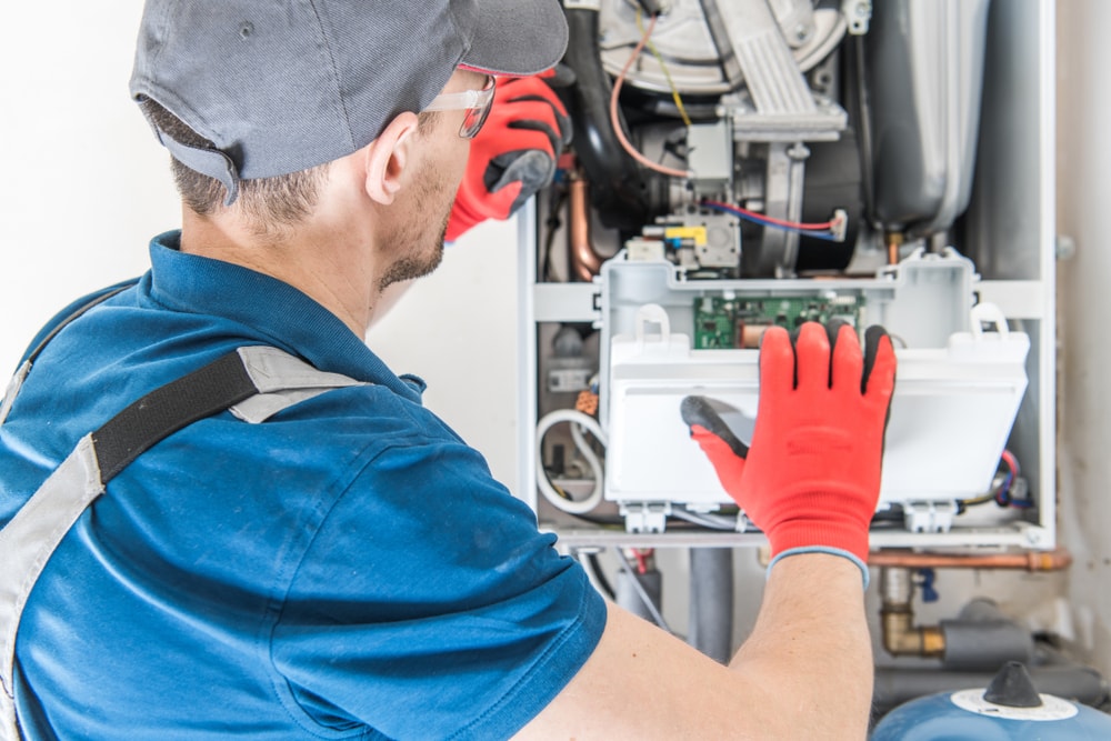 An image showing a furnace installer measuring the perfect size for a home to heat properly. 