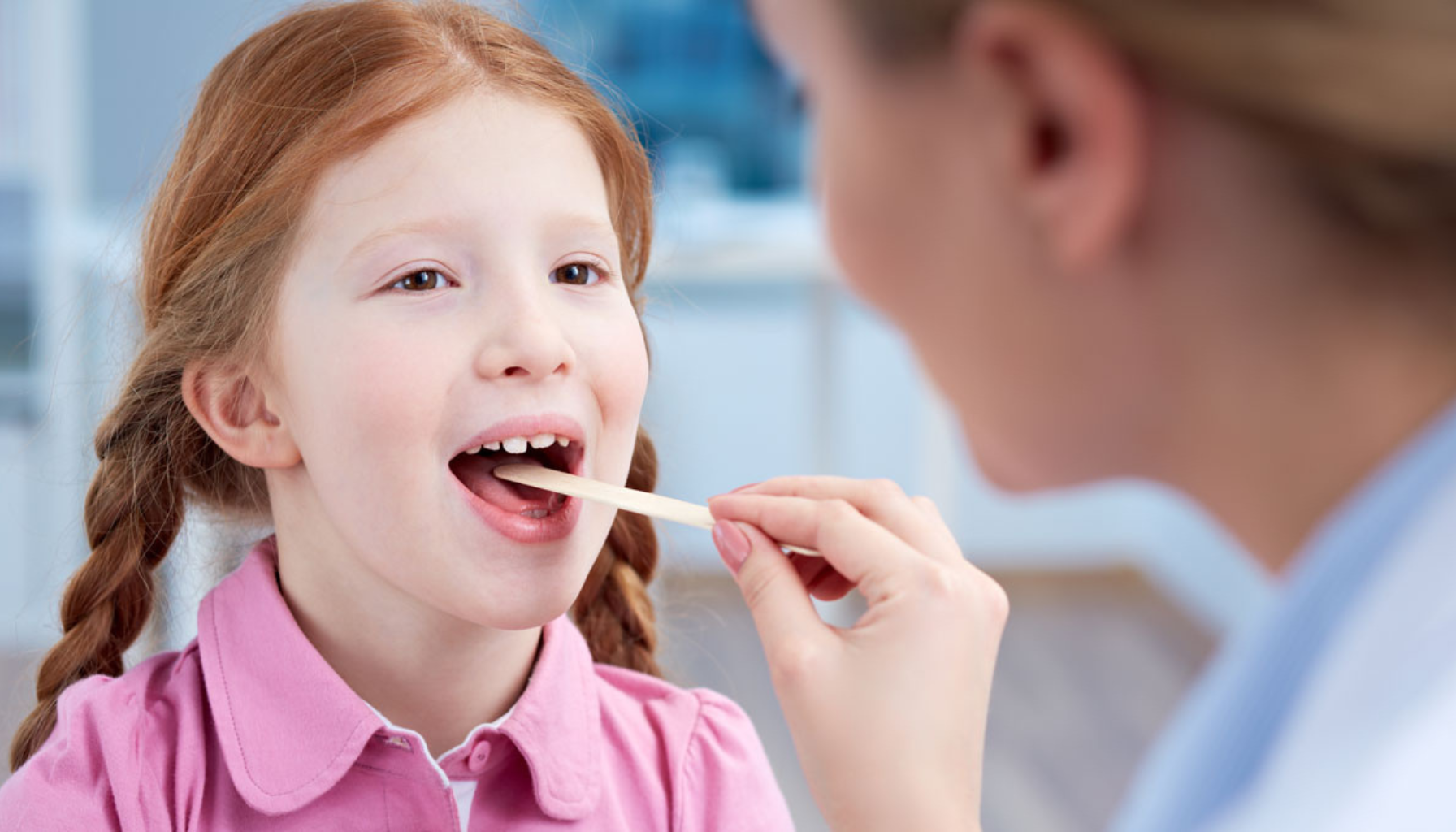 Lege undersøker halsen til en jente ved å bruke en trepinne for å se inn i munnhulen.
