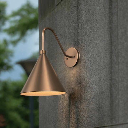Modern outdoor wall light with a bronze cone-shaped shade mounted on a curved arm against a stone wall.