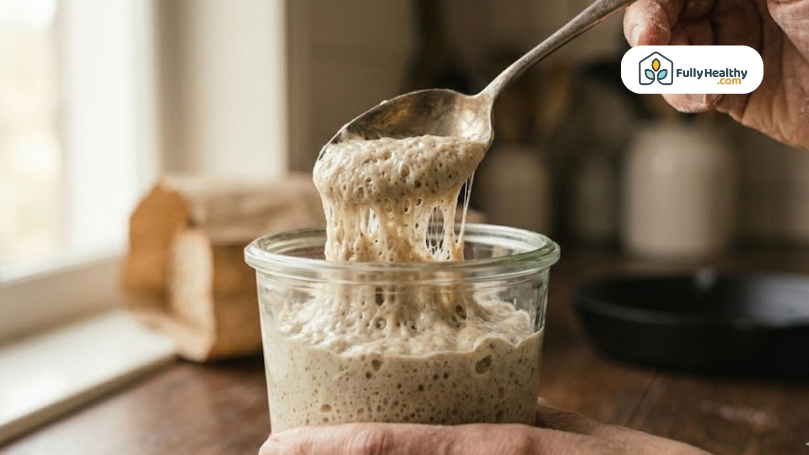 Spoon lifting bubbly active sourdough starter from jar