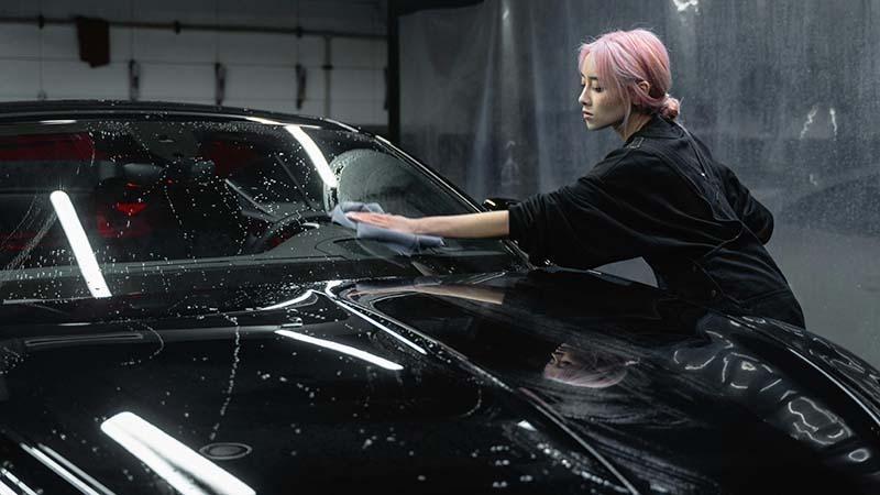 A woman drying a black car