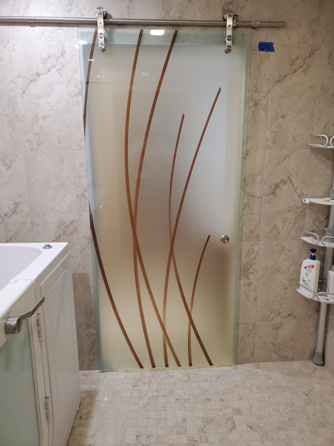 A bathroom with a barn door featuring glass panels