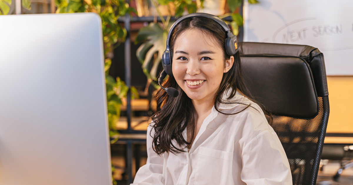 A smiling professional wearing a headset and working at a computer, discussing effective tax saving strategies in a modern office environment.