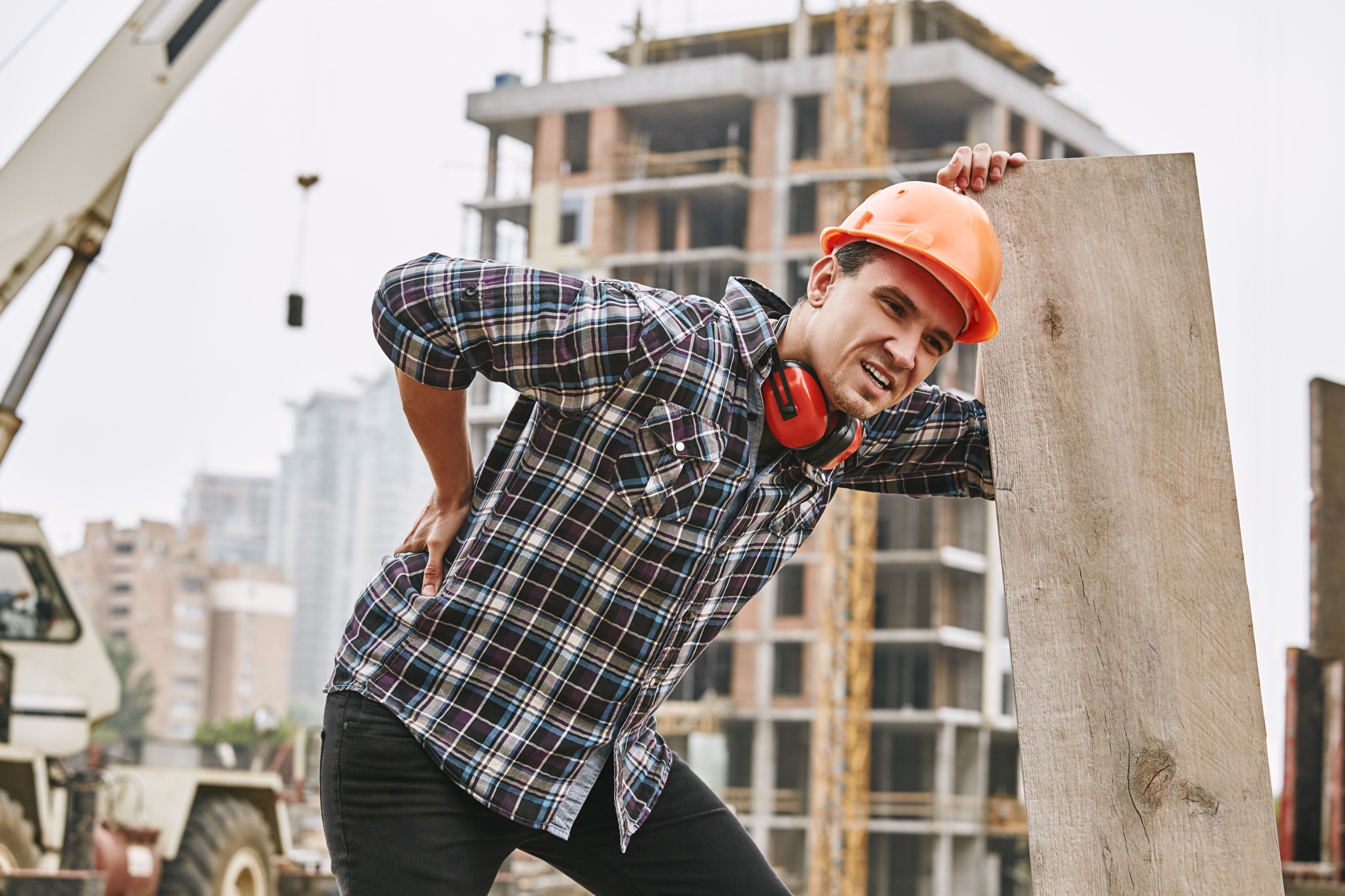 A construction worker with a back injury bending over in pain