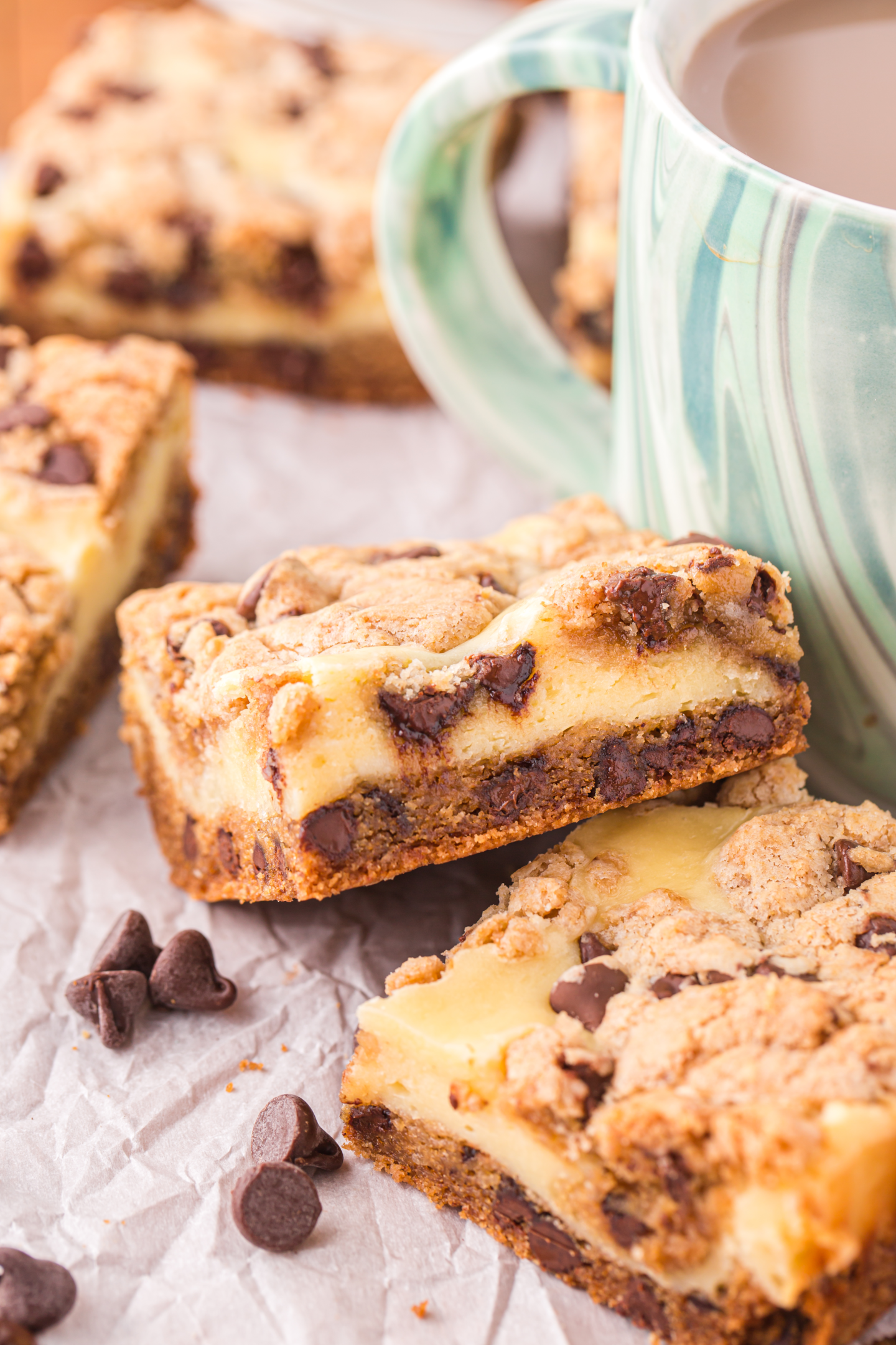 chocolate chip cheesecake bars next to a cup of coffee