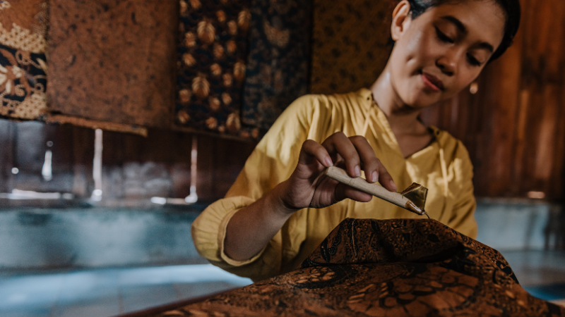 A person is repairing a piece of batik fabric