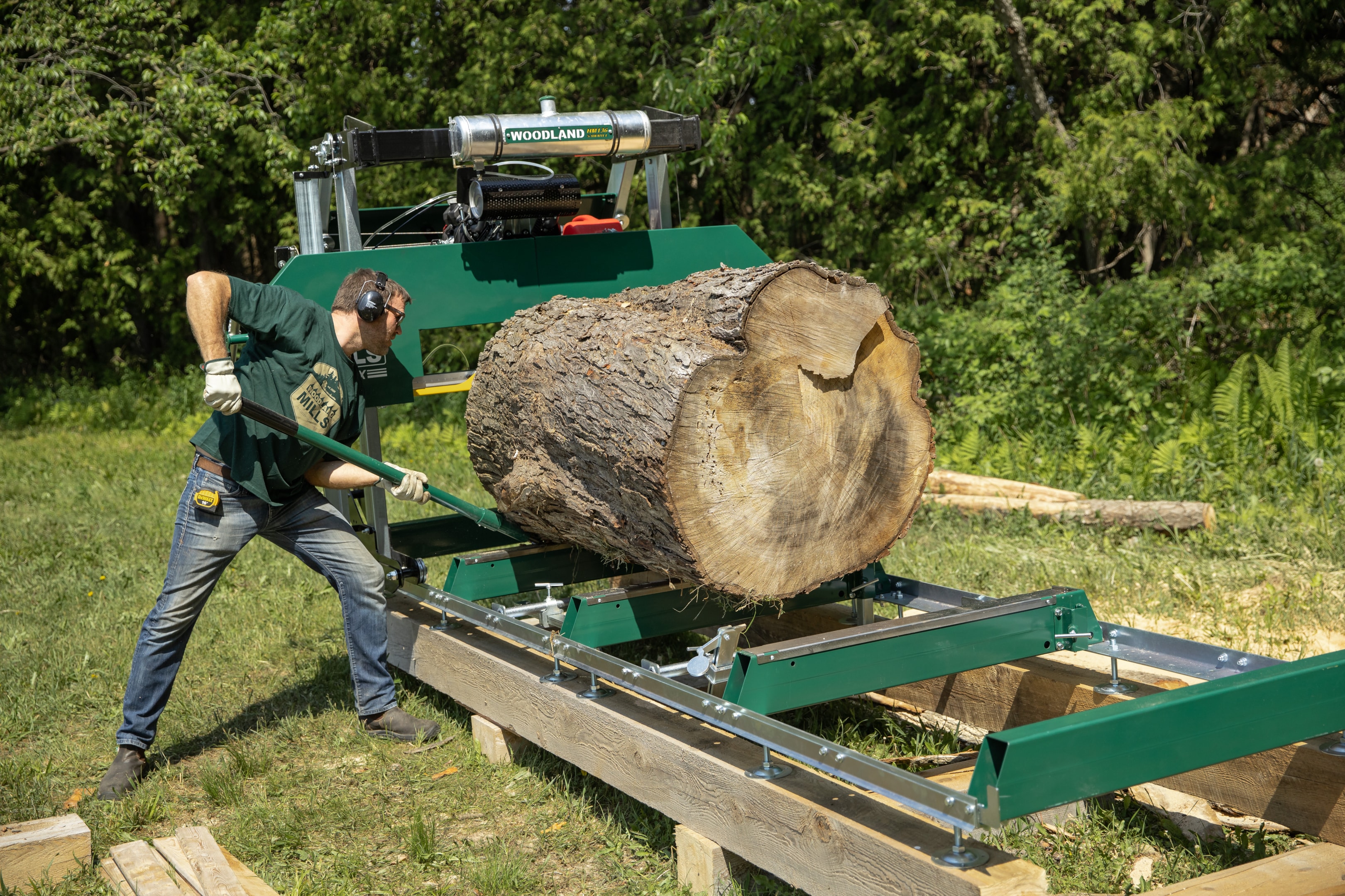 A cant hook being used to move a massive log on a portable sawmill.
