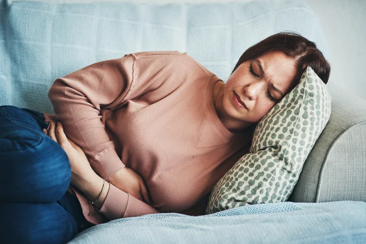 A woman lying on a sofa suffering from acid reflux