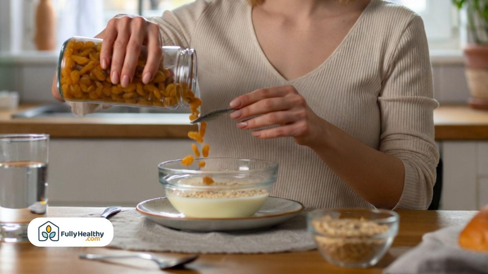 Person adding raisins into oatmeal during breakfast for a fiber-rich digestive wellness meal.