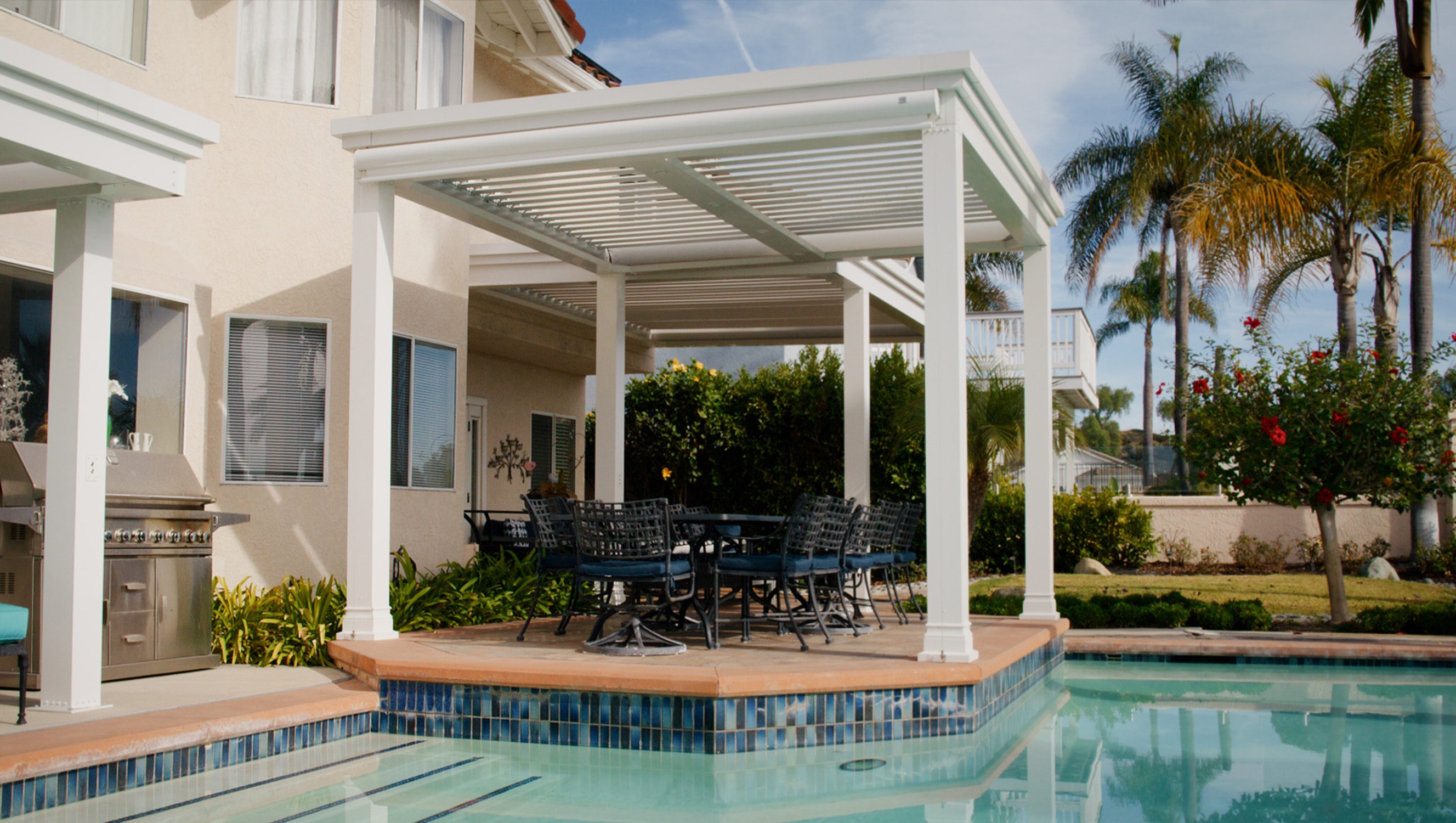 Poolside pergola with outdoor seating and small outdoor kitchen.