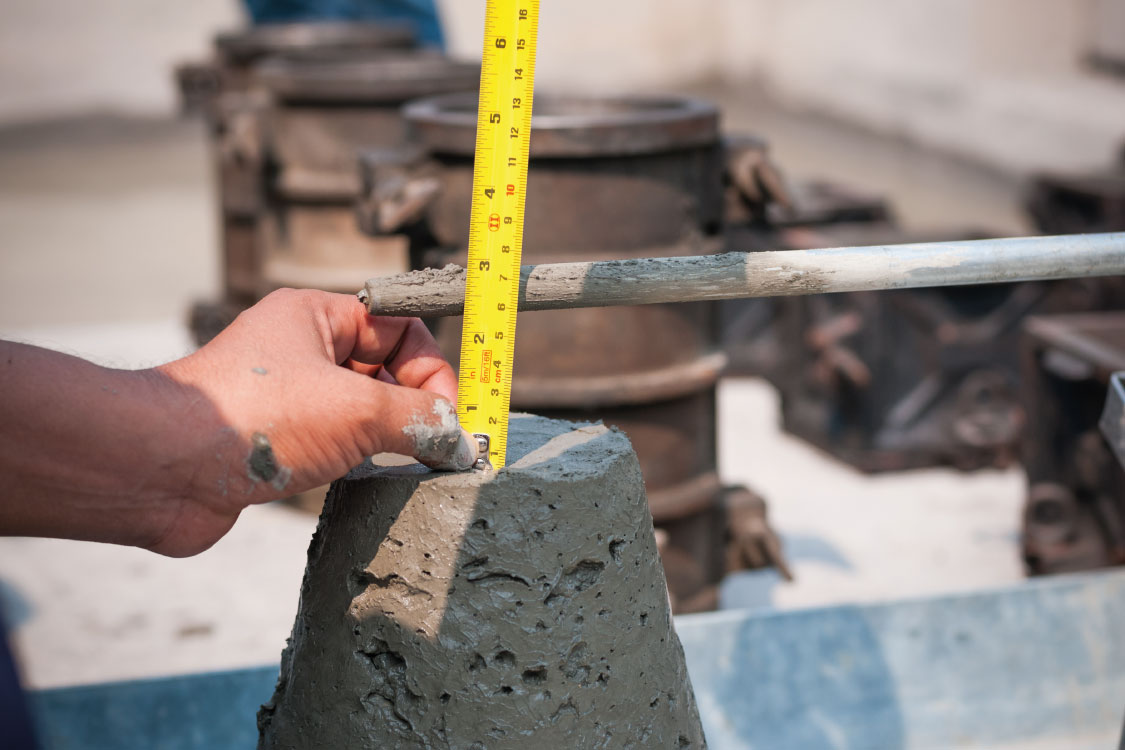 A technician performing a slump test on freshly mixed concrete