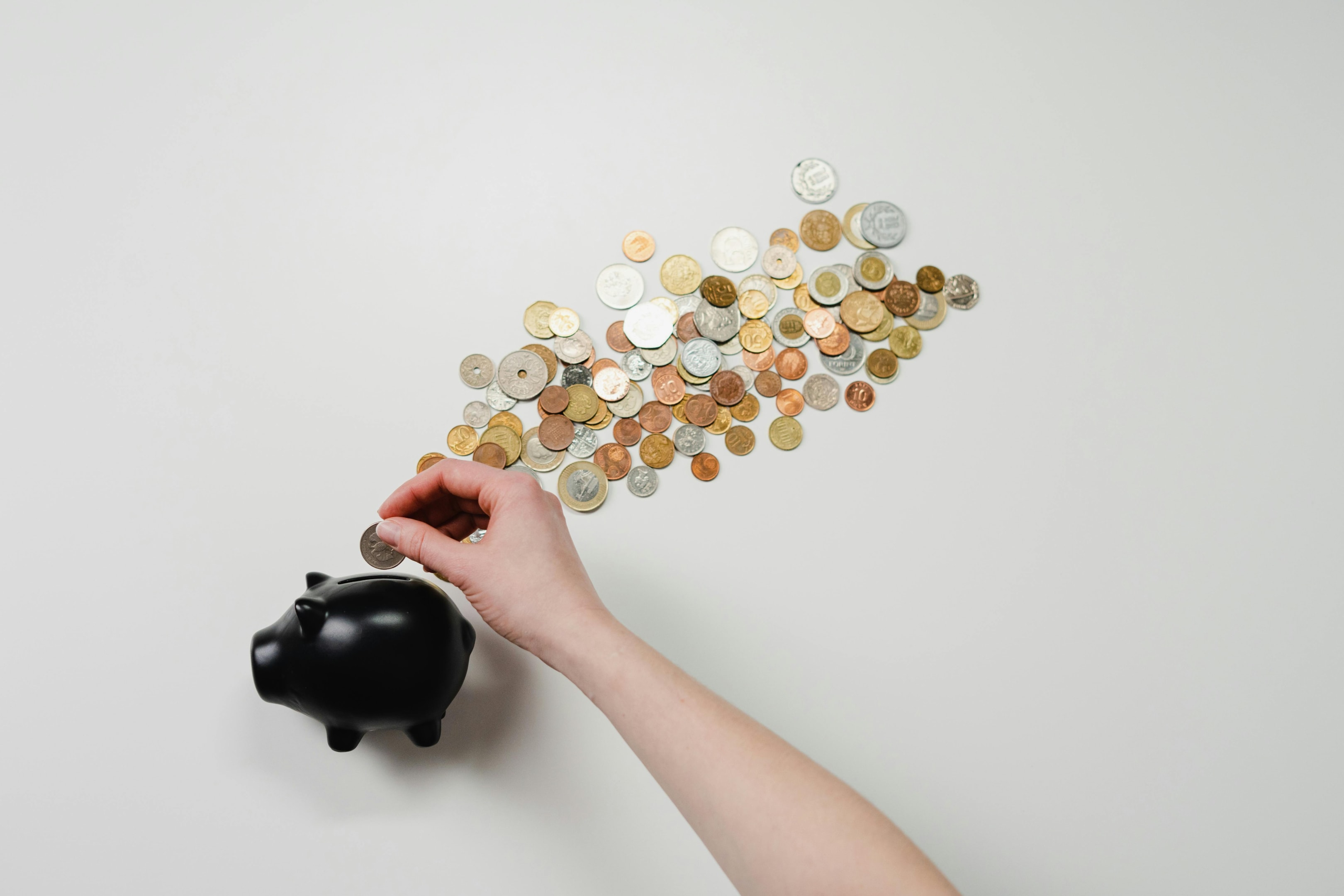 Coins being put into a piggy bank. 