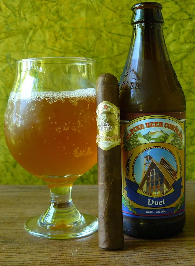 A picture of a person enjoying a Dona Nieves cigar with a glass of beer